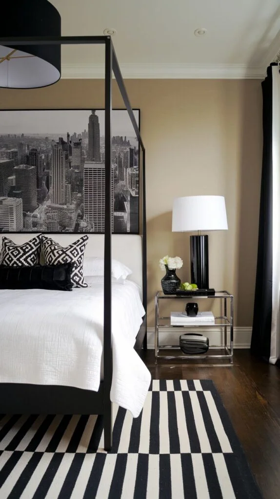 Black and white bedroom with tall four-poster bed and striped rug.