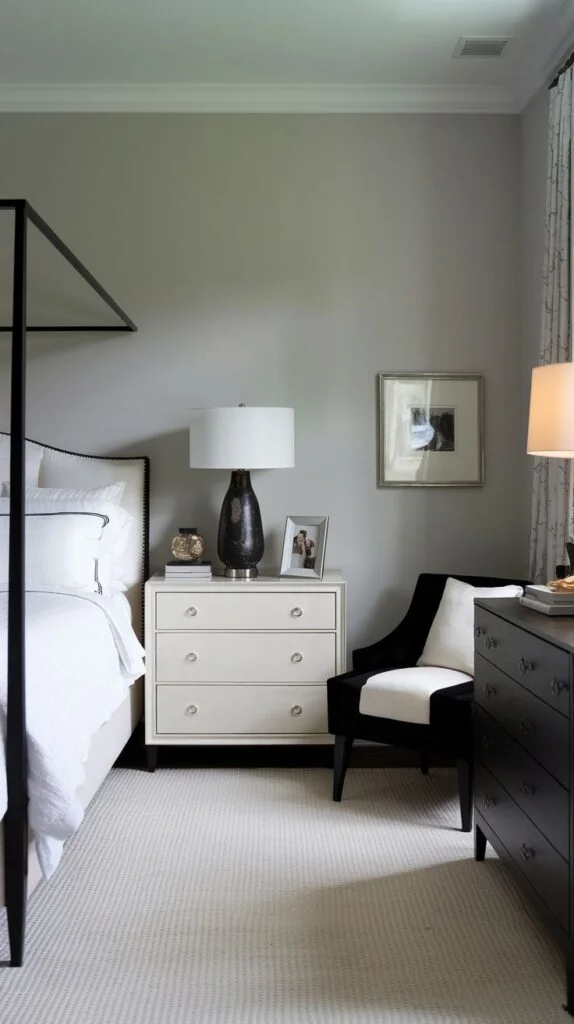 Neutral bedroom with black four-poster bed, white dresser, and black and white accent chair.