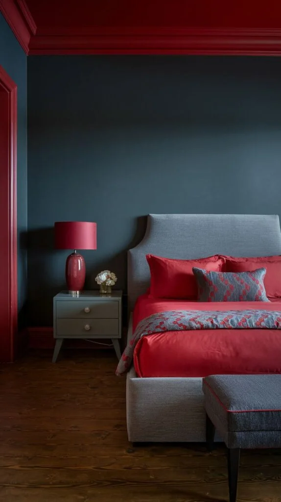 Bedroom with deep blue walls, red trim, and red bedding on grey upholstered bed.