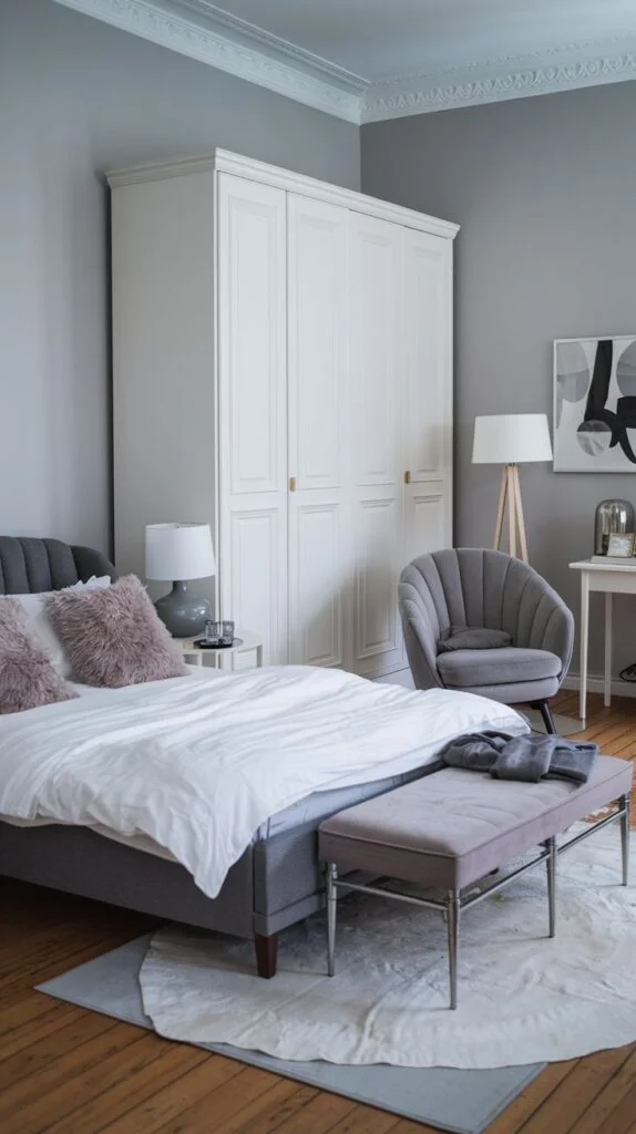 Bedroom with light grey walls, white wardrobe, and grey upholstered bed