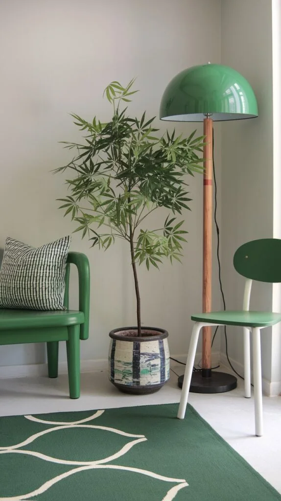 A minimalistic yet comfortable green corner featuring a bright green bench and a light green chair with a white frame. A large leafy plant in a patterned pot and a green rug with a white wavy design add natural elements to this serene green space.