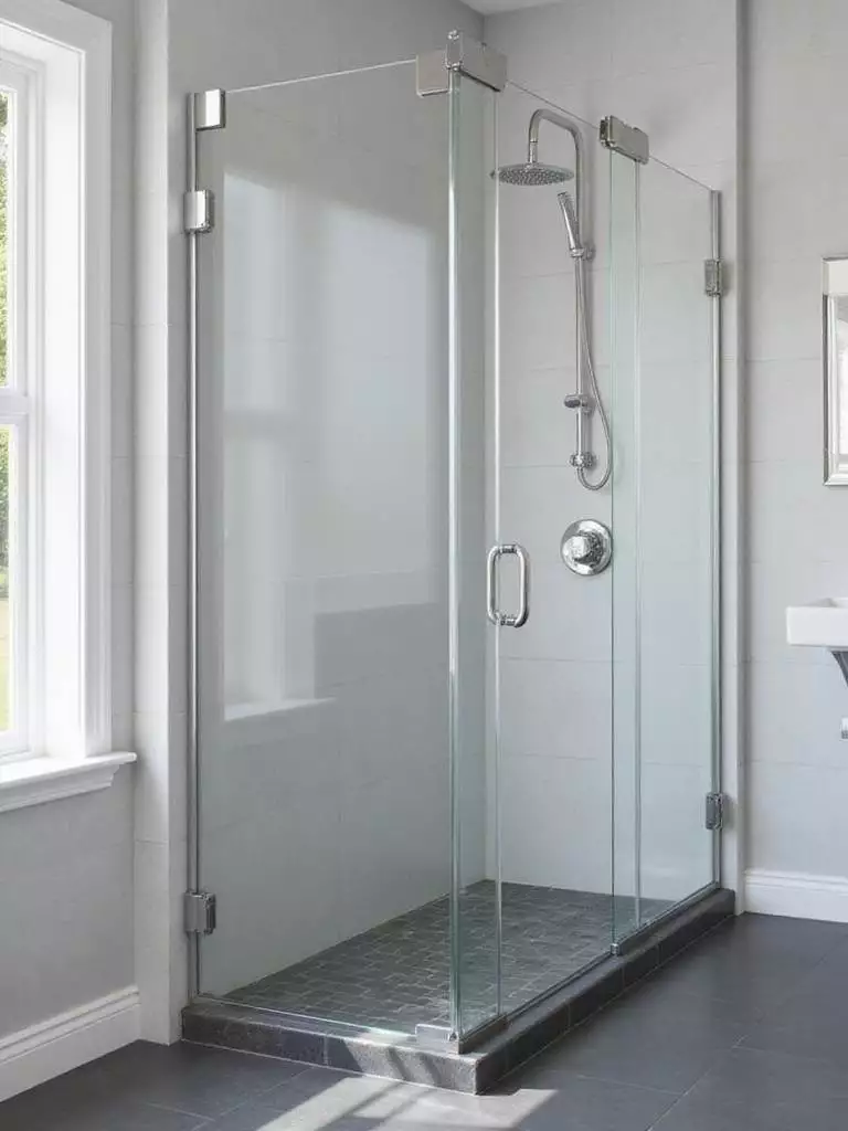 Modern bathroom with frameless pivot shower door and light grey tiles.