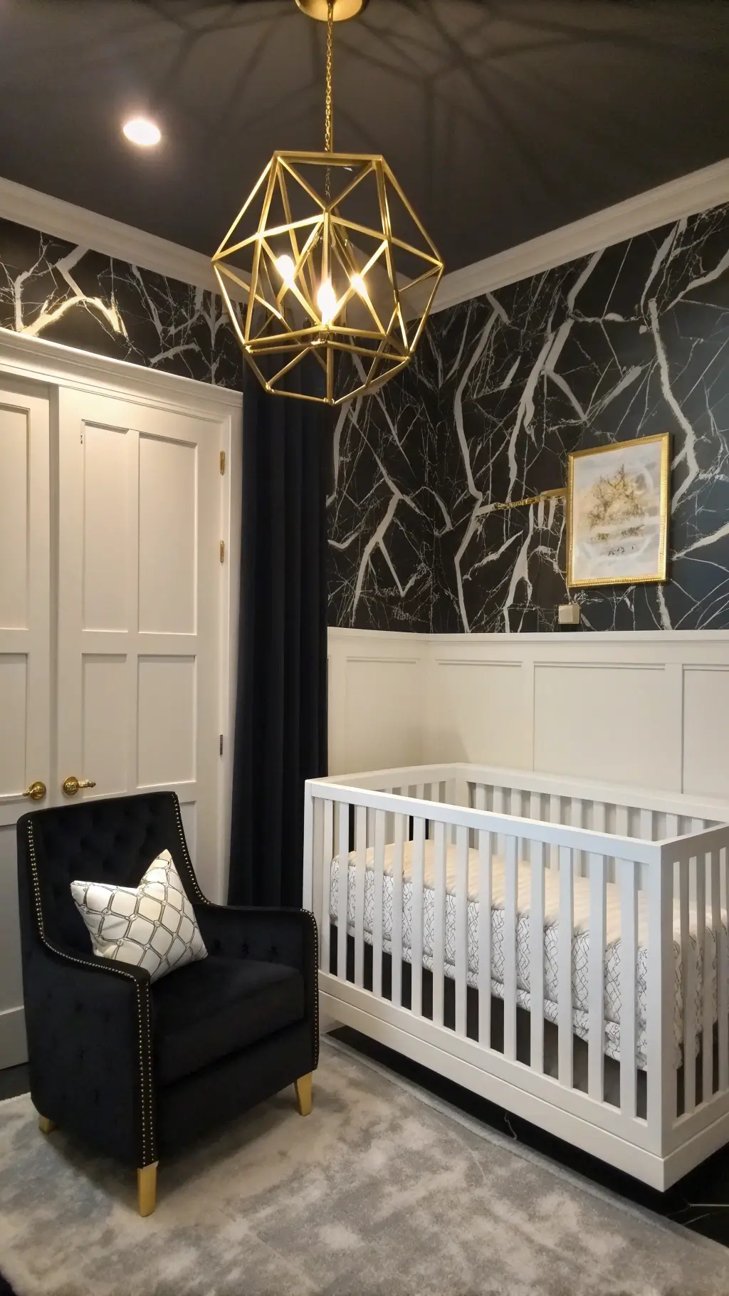 Art deco nursery with black and white color scheme, spindle crib, gold geometric light fixture, velvet rocker, and marble-print wallpaper under dramatic evening lighting