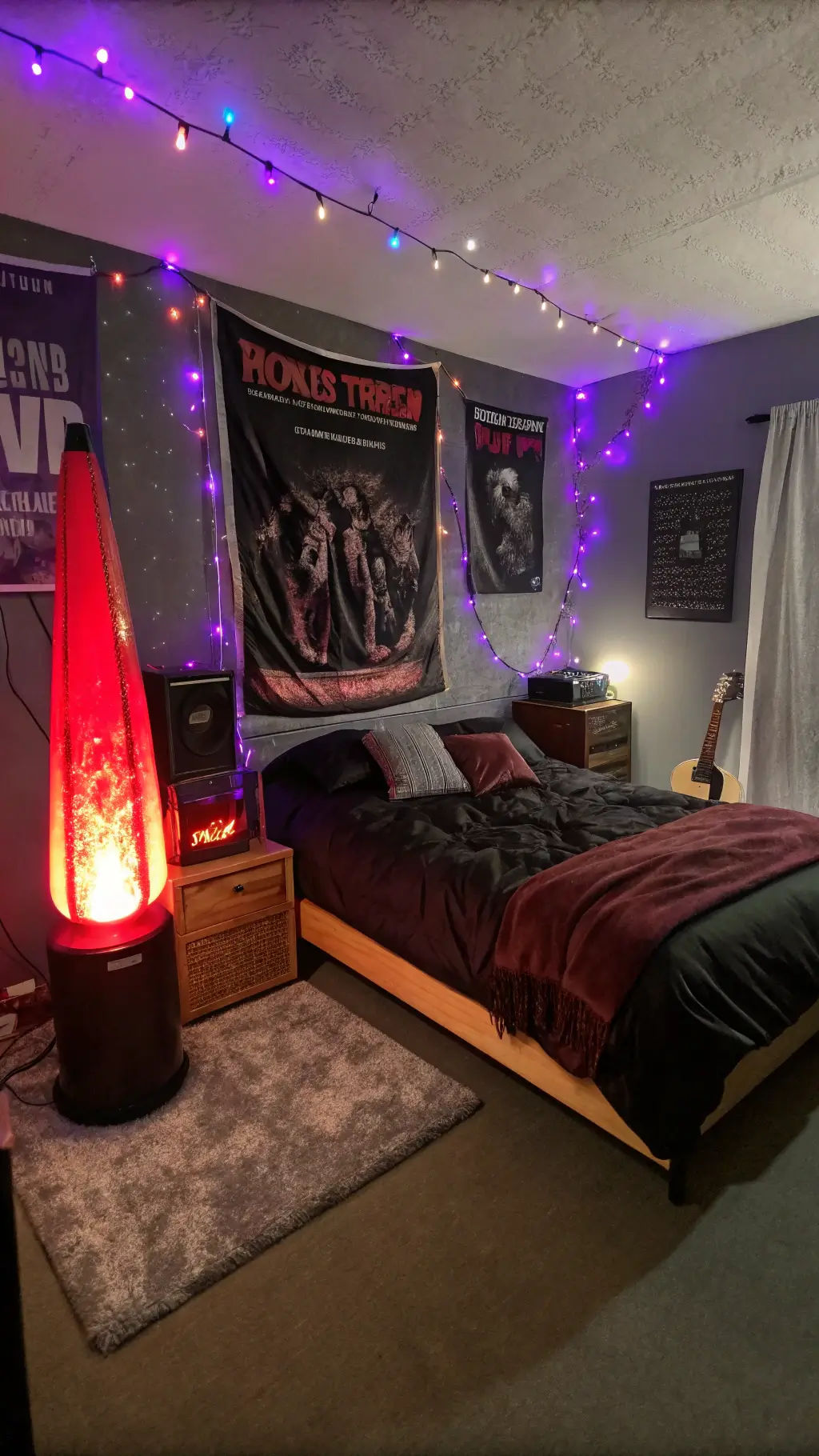 Grunge bedroom at midnight lit by red lava lamp, purple LED lights, string lights, music festival posters, moth-eaten tapestry, rumpled king bed with black and burgundy bedding, vintage amp as nightstand.