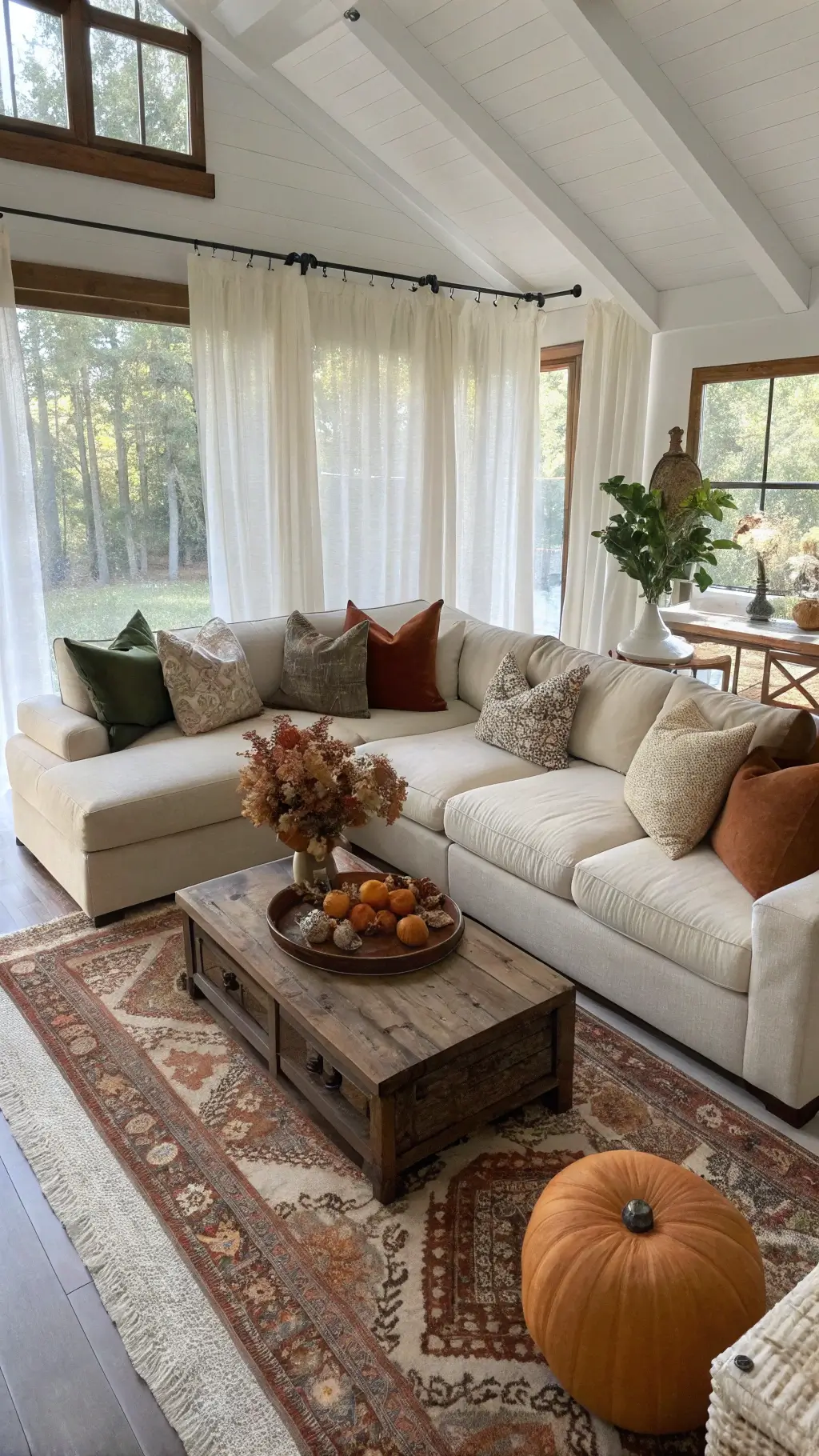 High-angle view of a cozy modern-rustic living room with morning sunlight, oatmeal bouclé sectional, velvet pillows, reclaimed wood coffee table, layered jute and wool rugs, copper side tables, and vintage pottery
