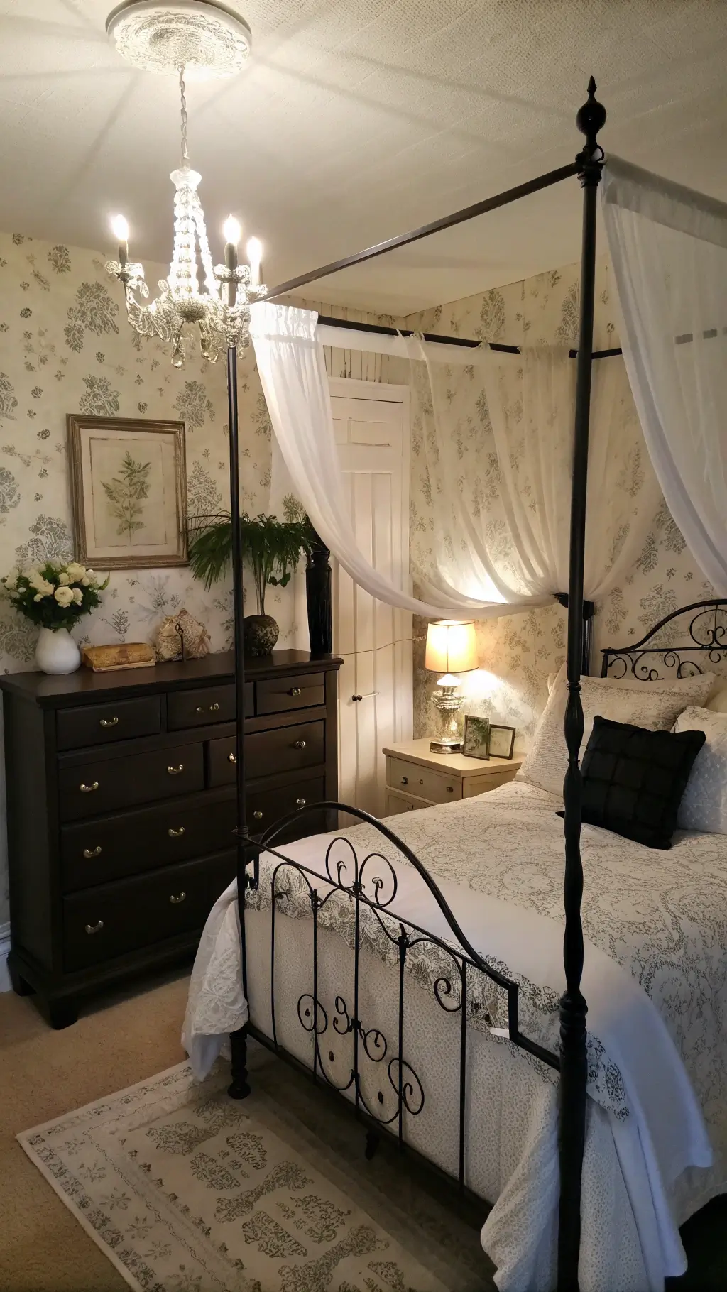 Cozy bedroom at dusk featuring a black iron canopy bed with white curtains and bedding, vintage dresser, textured wallpaper, and mercury glass lamps, shot from a corner for an intimate atmosphere