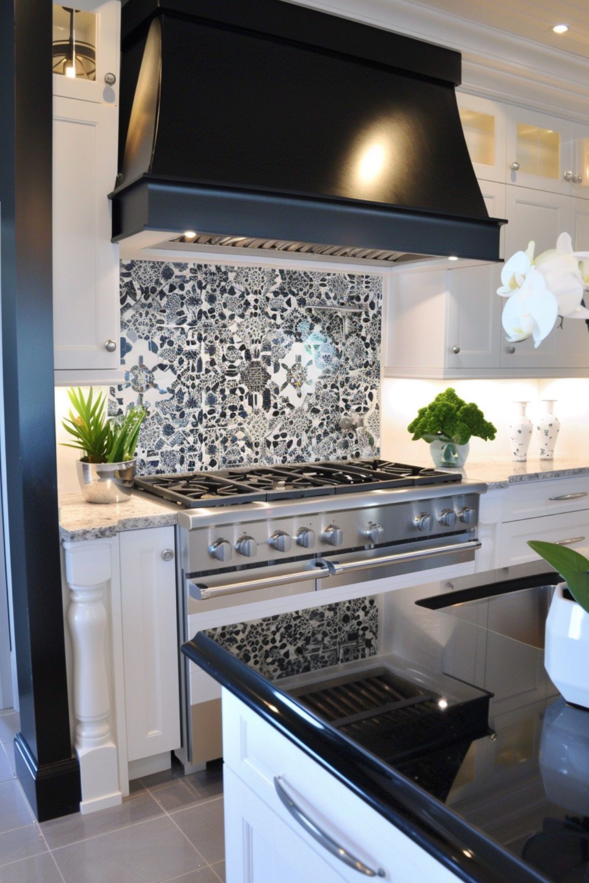 Stainless steel oven with black and white patterned tile backsplash and black range hood.