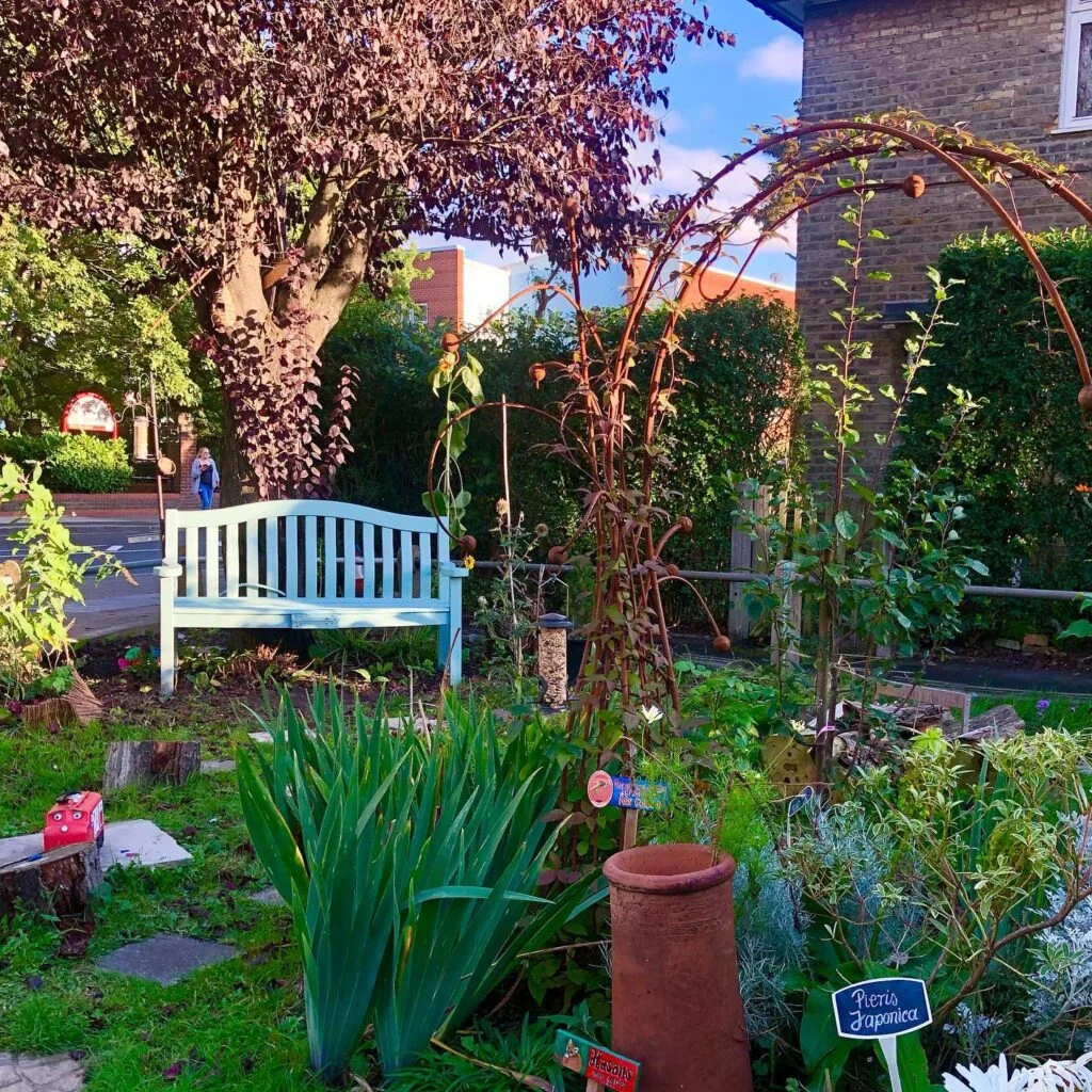 Community garden corner with white bench and copper trellises