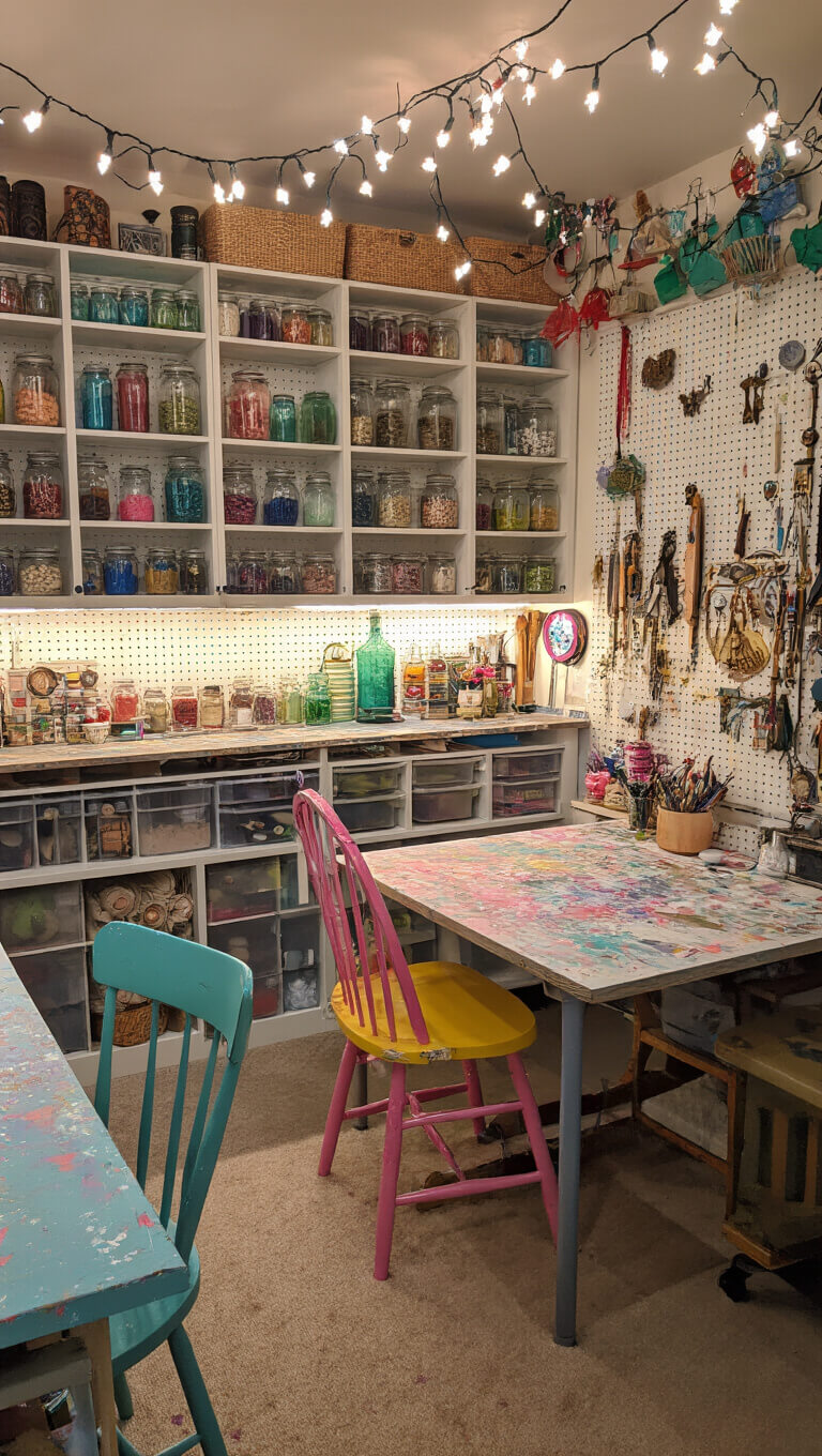 Eclectic craft room with string lights, colorful storage jars, candy-colored furniture, and pegboard of creative tools.